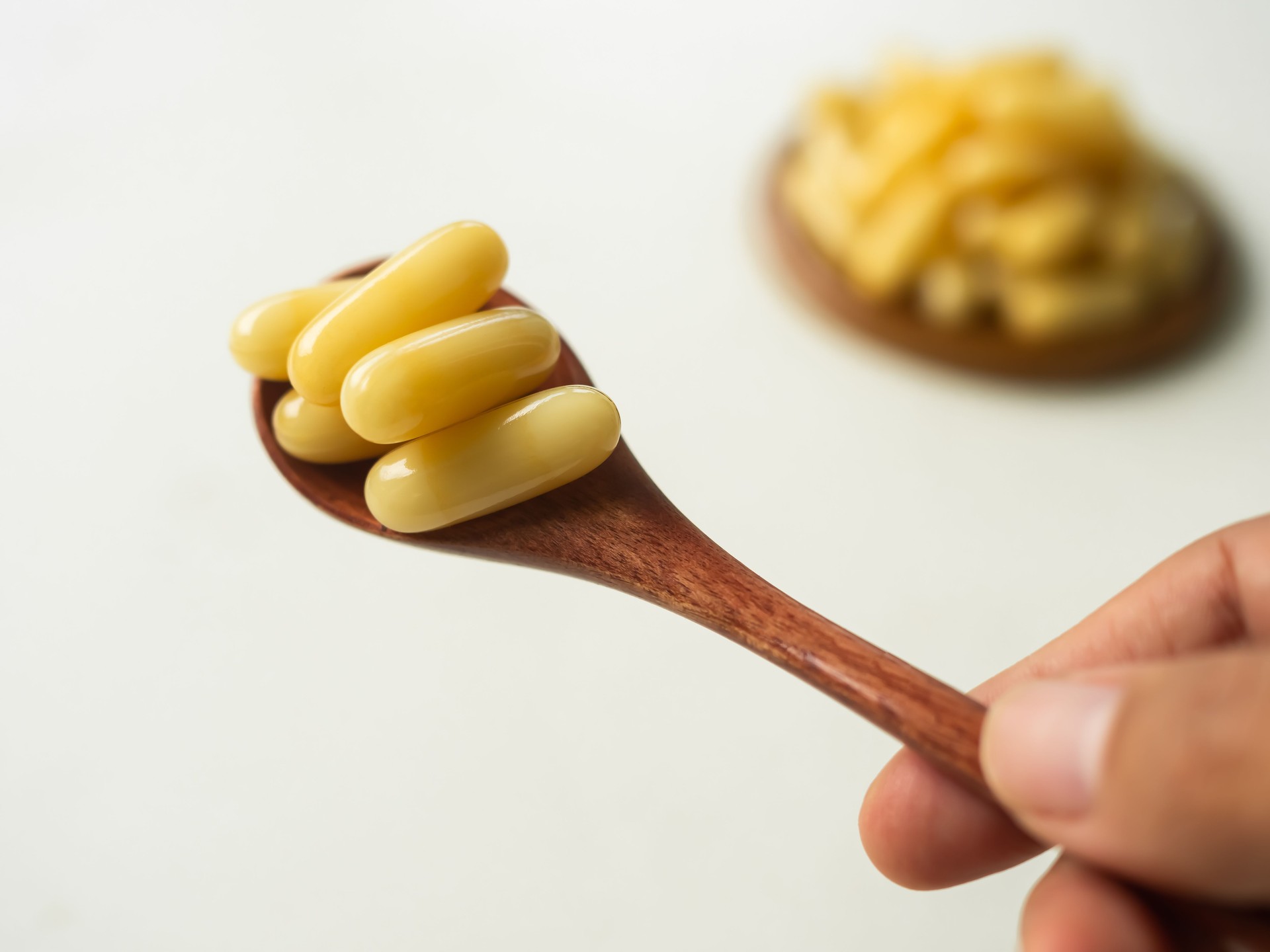 Royal jelly capsules on wooden spoon.
